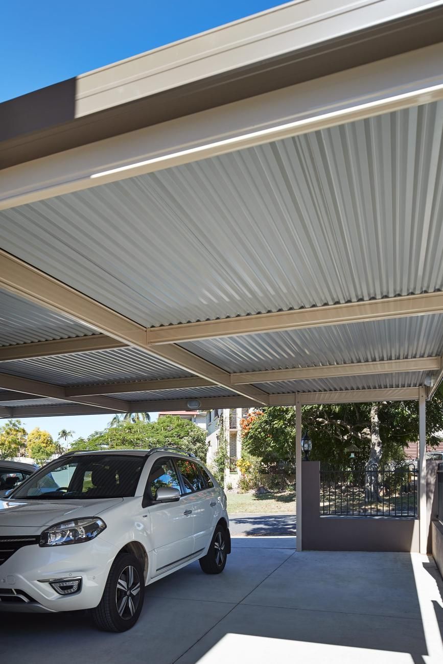 A Car Is Parked Under A Carport In Front Of A House — Austeel Sheds in Bowen, QLD
