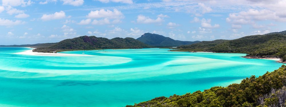 An Aerial View Of A City With A Beach And Mountains In The Background. — Austeel Sheds in Collinsville, QLD