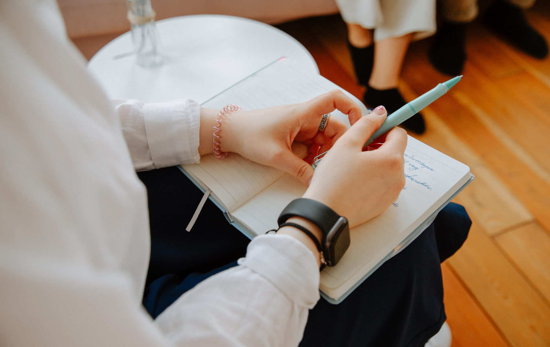 A woman is sitting on a couch writing in a notebook.