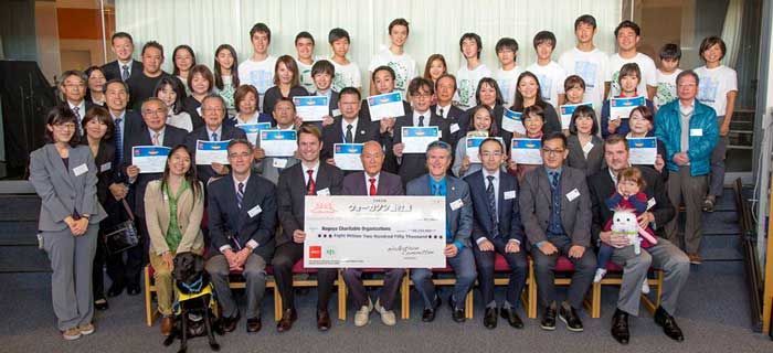 A large group of people are posing for a picture with a large ceremonial cheque.