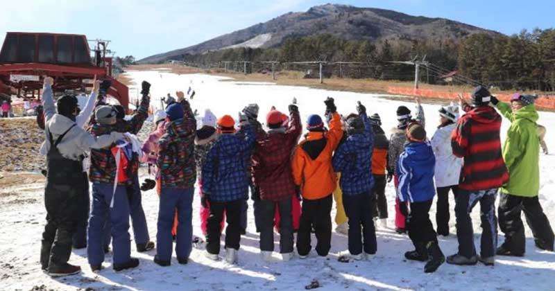 A group of people are standing in the snow with their arms in the air.