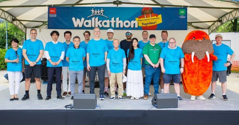 A group of people standing on a stage in front of a sign that says walkathon.