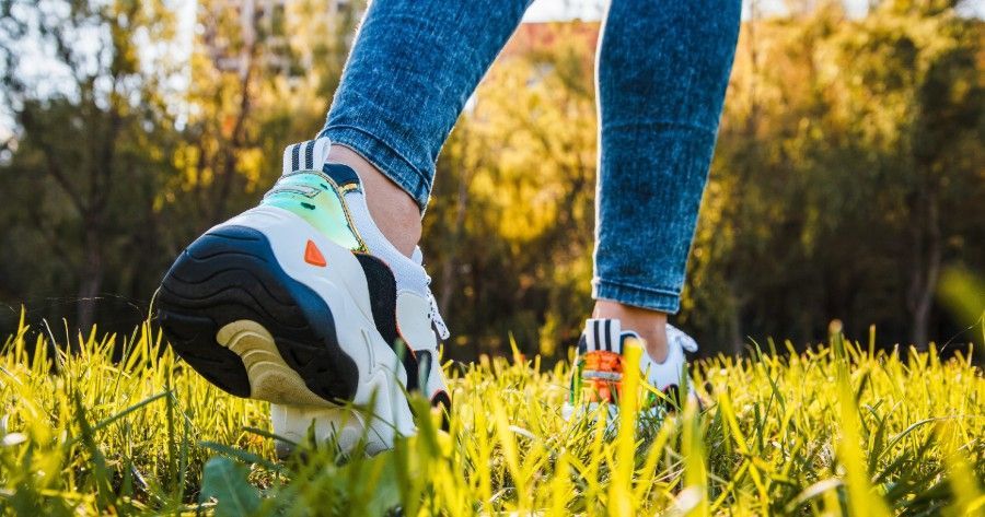 屋外の芝生の上を歩く人の足元。35日間ウォークチャレンジを象徴するイメージ