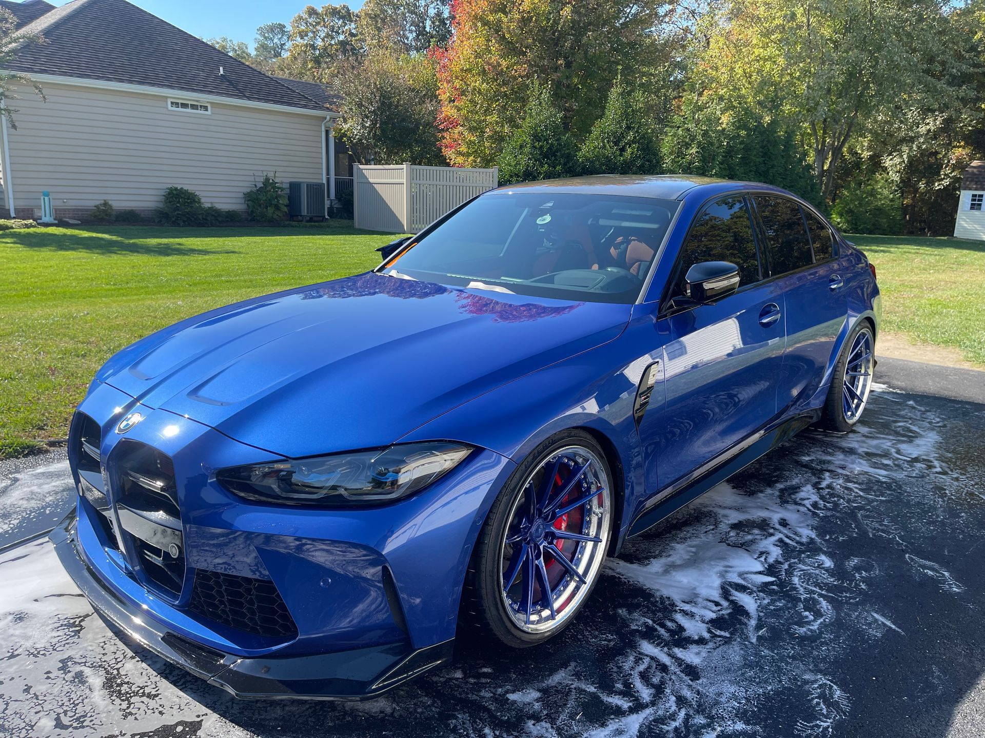 A person wearing blue gloves is polishing the hood of a white car.