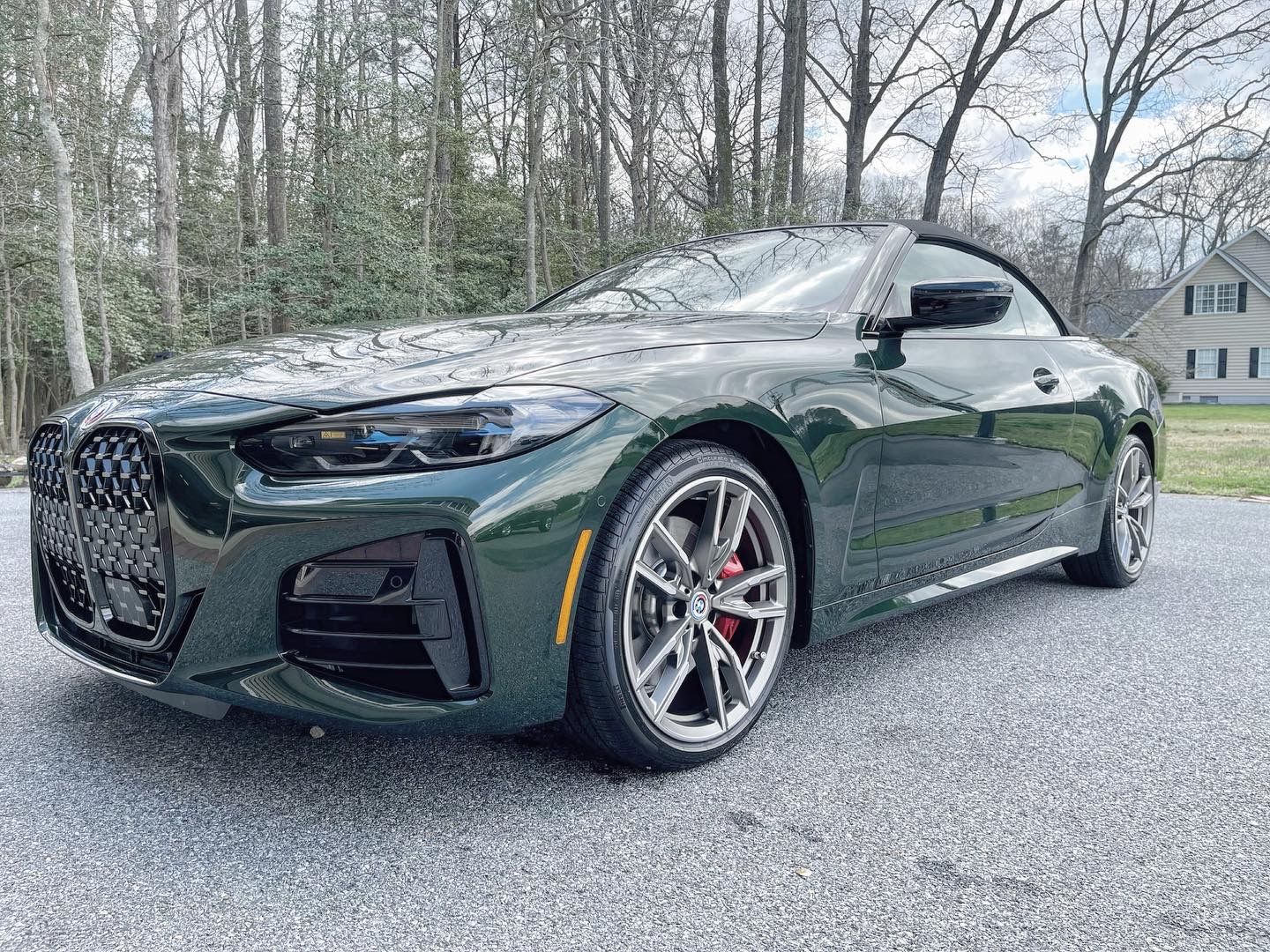 A green bmw 4 series convertible is parked in a driveway.