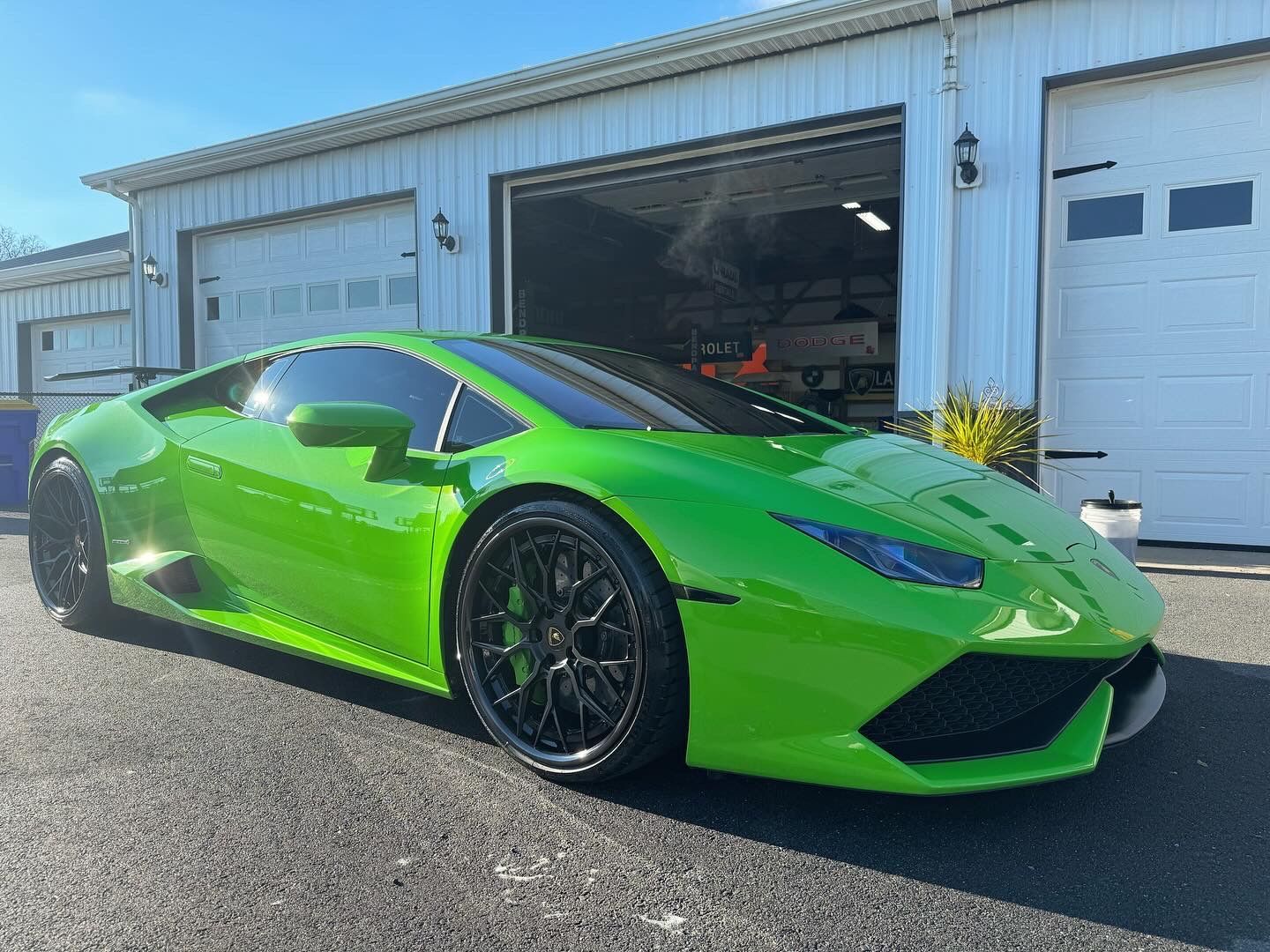 A green lamborghini huracan is parked in front of a garage.