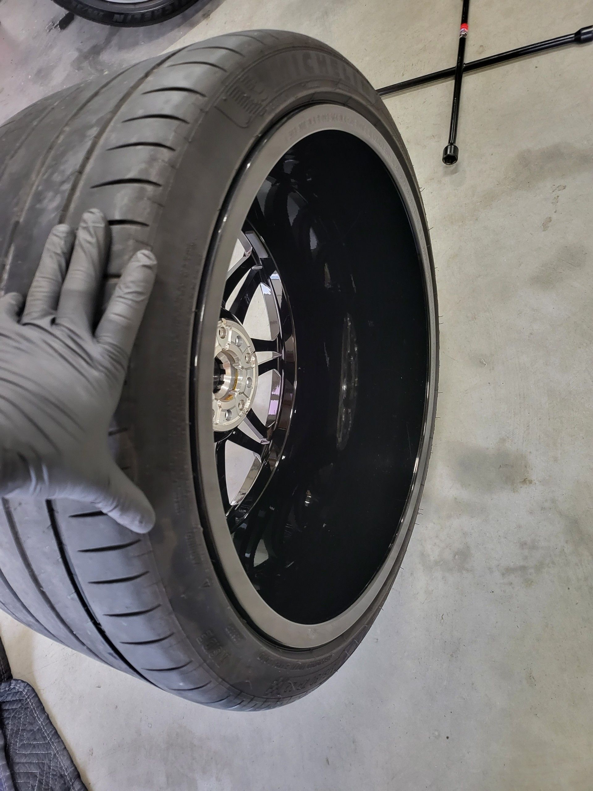 A person wearing black gloves is touching a tire