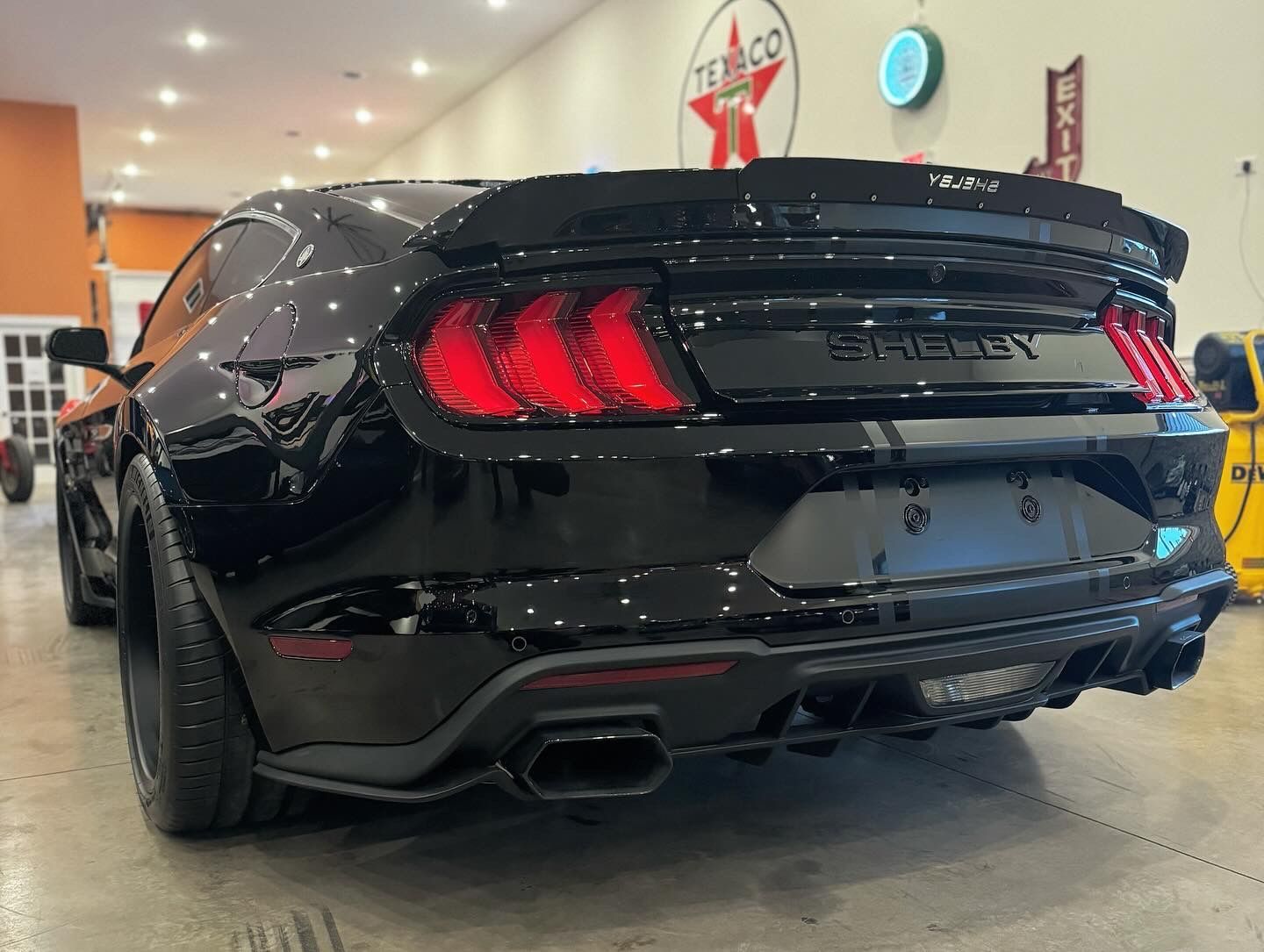 A black ford mustang is parked in a garage.