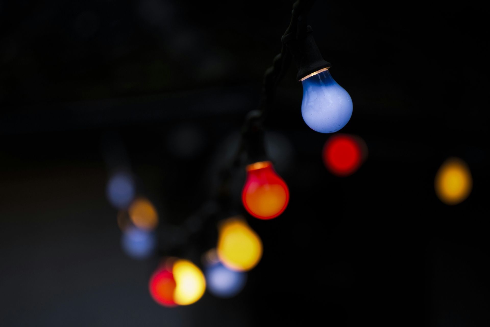 String of colorful lights against a dark background. Blue, red, and yellow bulbs are visible.