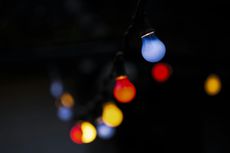 String of colorful lights against a dark background. Blue, red, and yellow bulbs are visible.