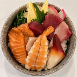 Assorted sushi and sashimi in a gray bowl on a marble table