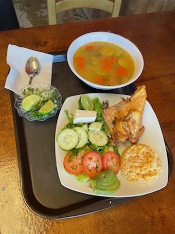 A plate of food with a bowl of soup and a salad on a tray on a table.