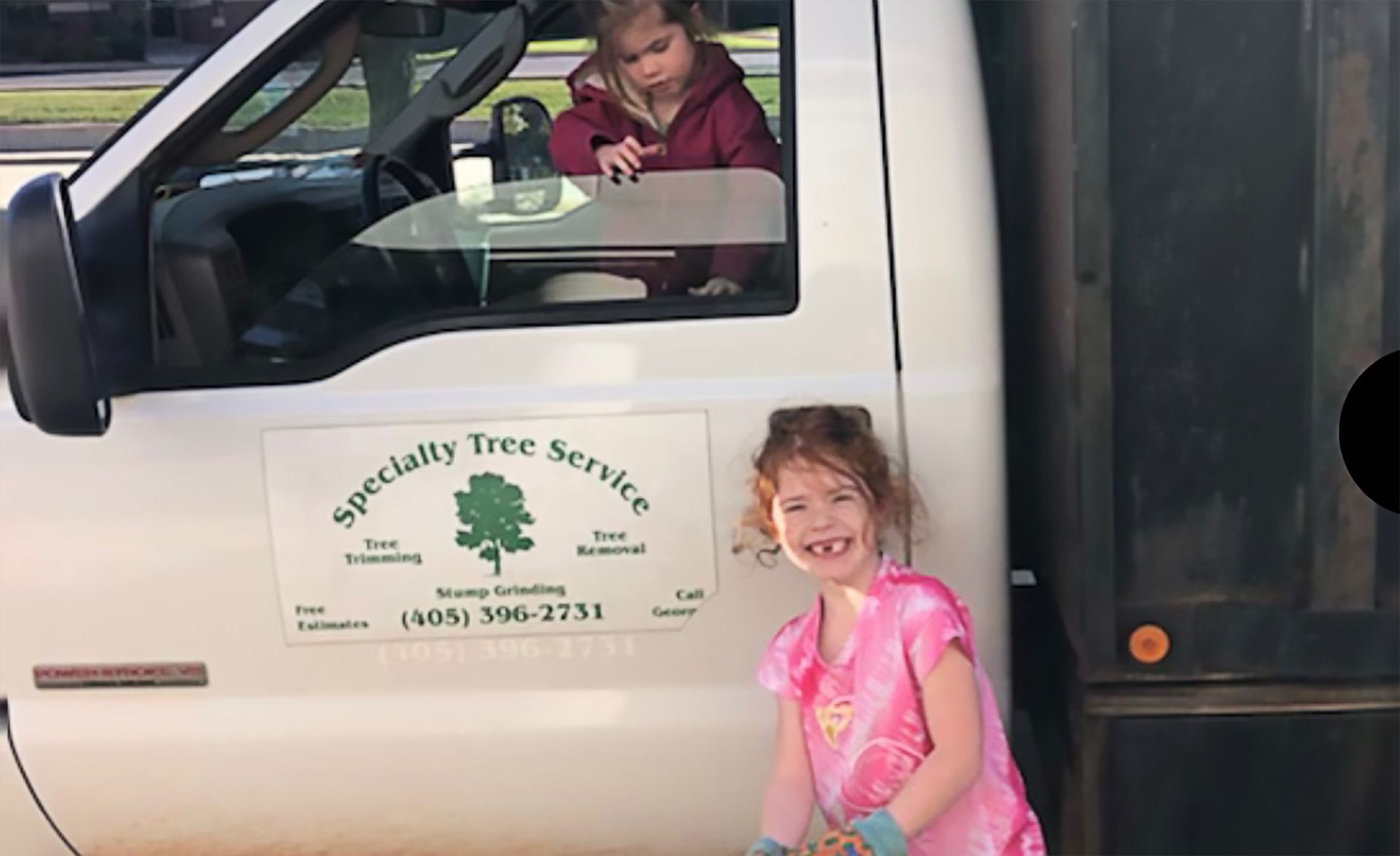 Two children pose by a white truck.