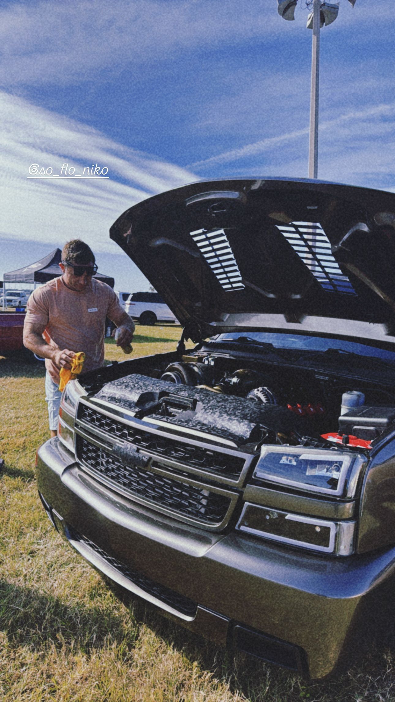 A man is standing next to a truck with the hood open