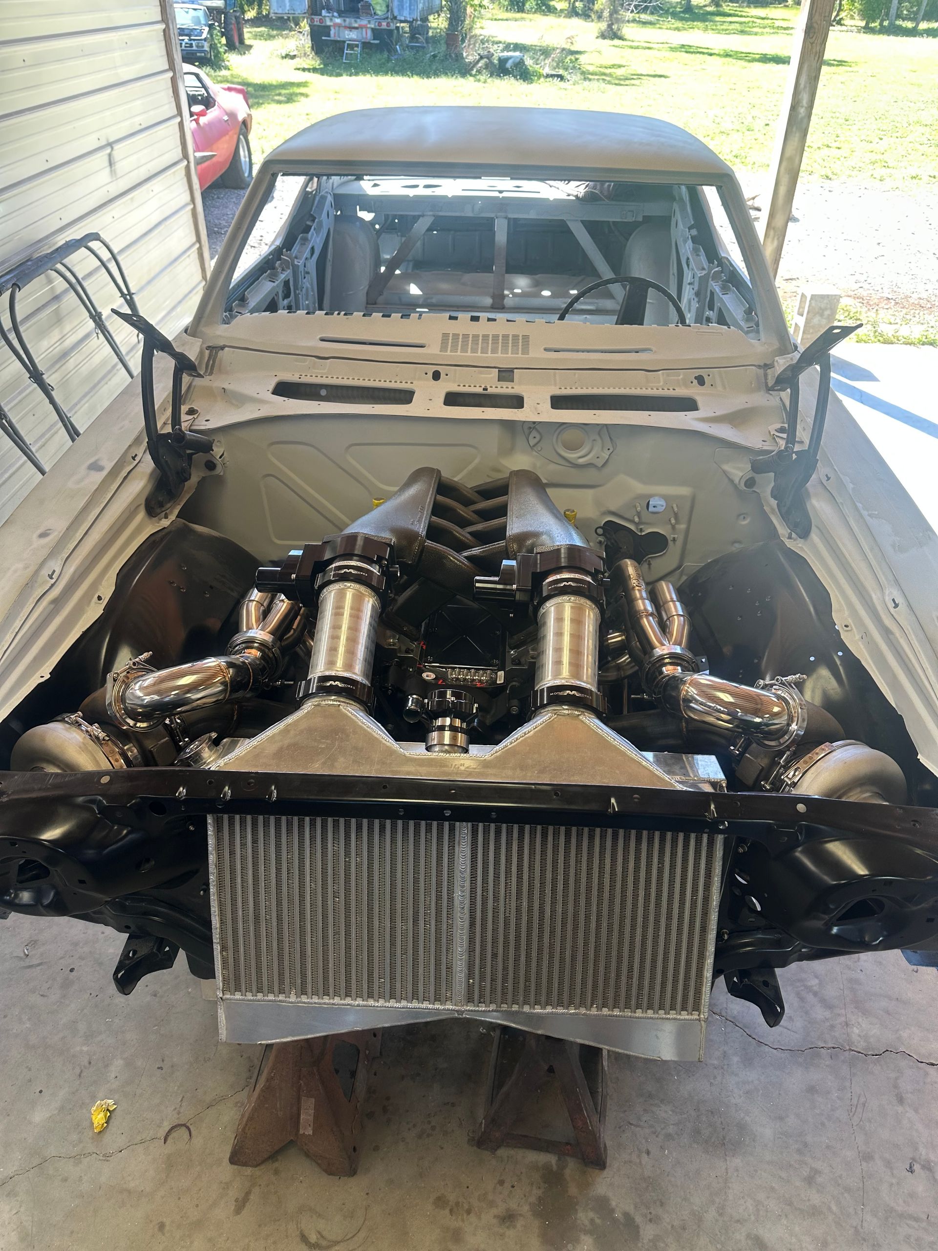 A car with the engine removed is sitting on a wooden stand.