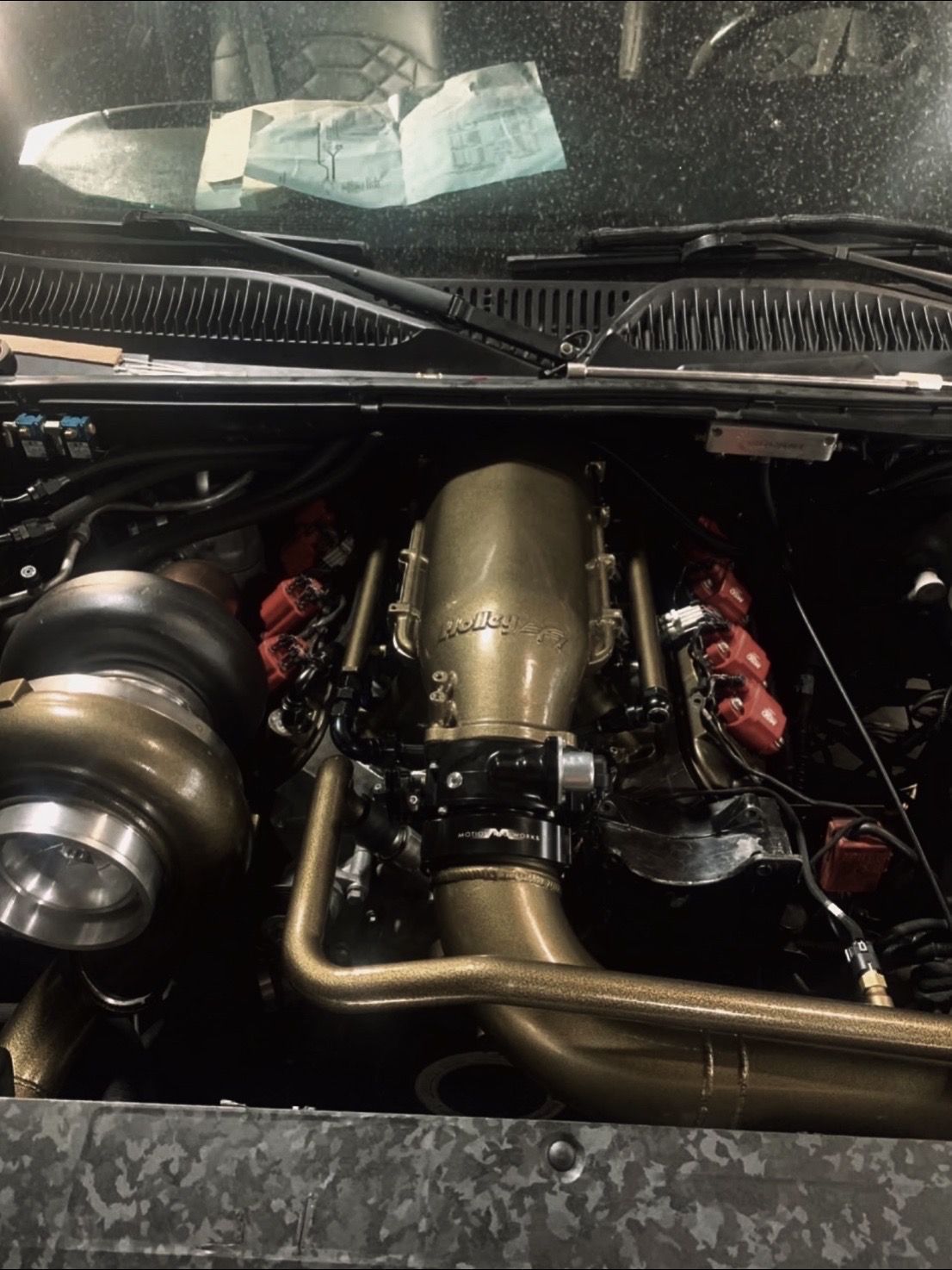 A close up of the engine of a car with the hood open.