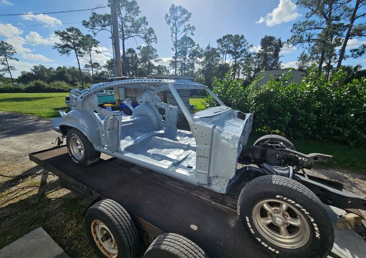 A white car is sitting on top of a trailer.