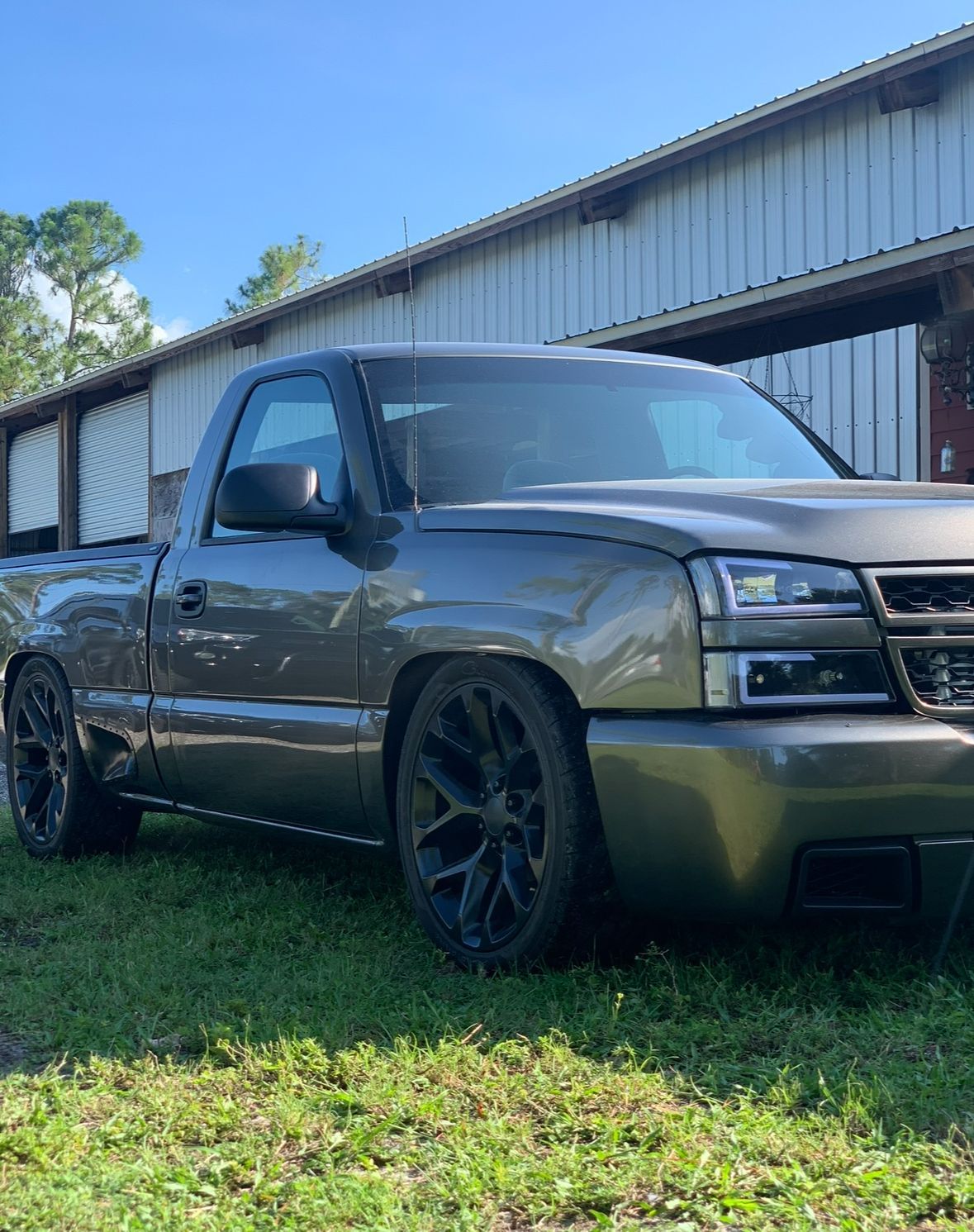A gray truck is parked in the grass in front of a building.