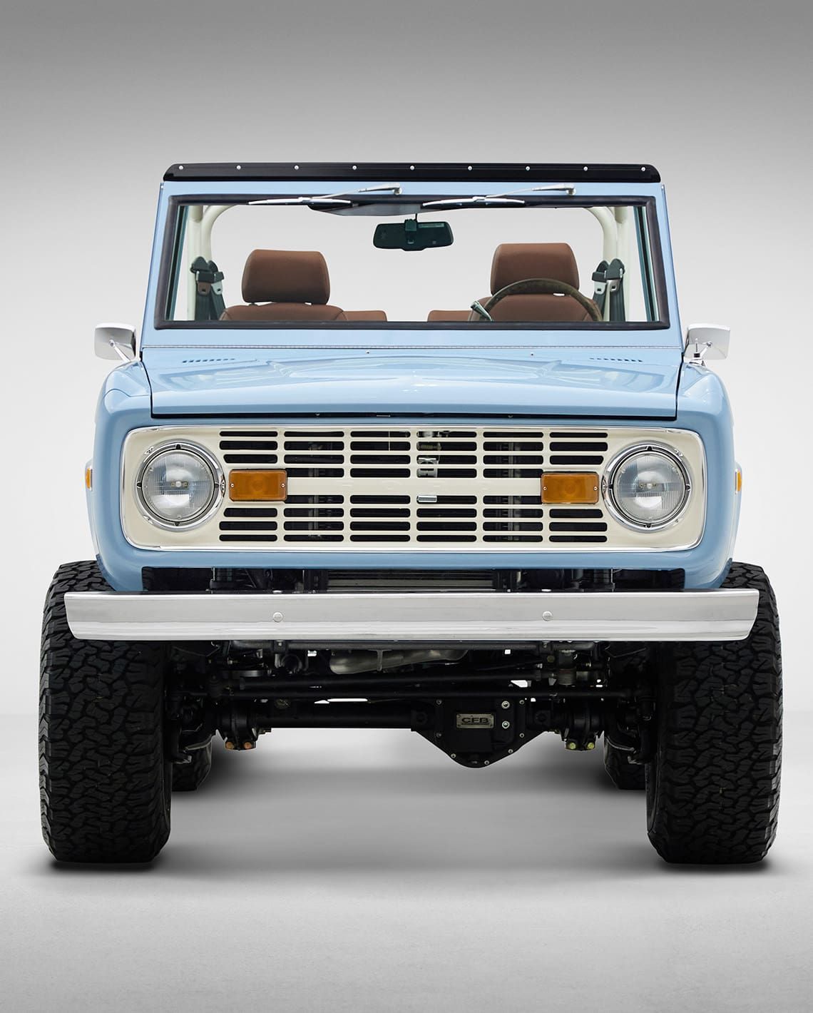A light blue ford bronco is parked on a white surface.