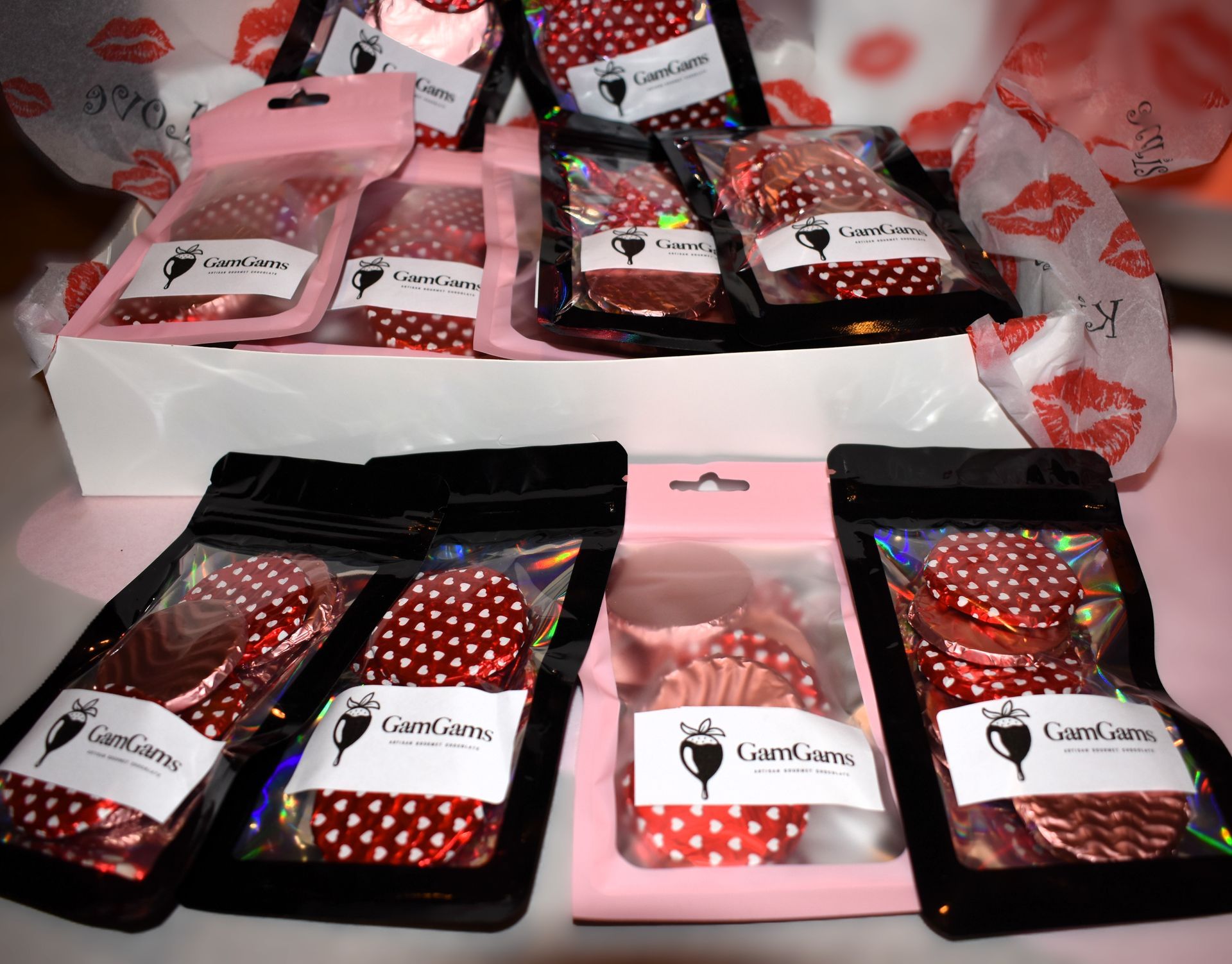 Variety of foil cupcake liners in bags, with a logo, presented in a white box.