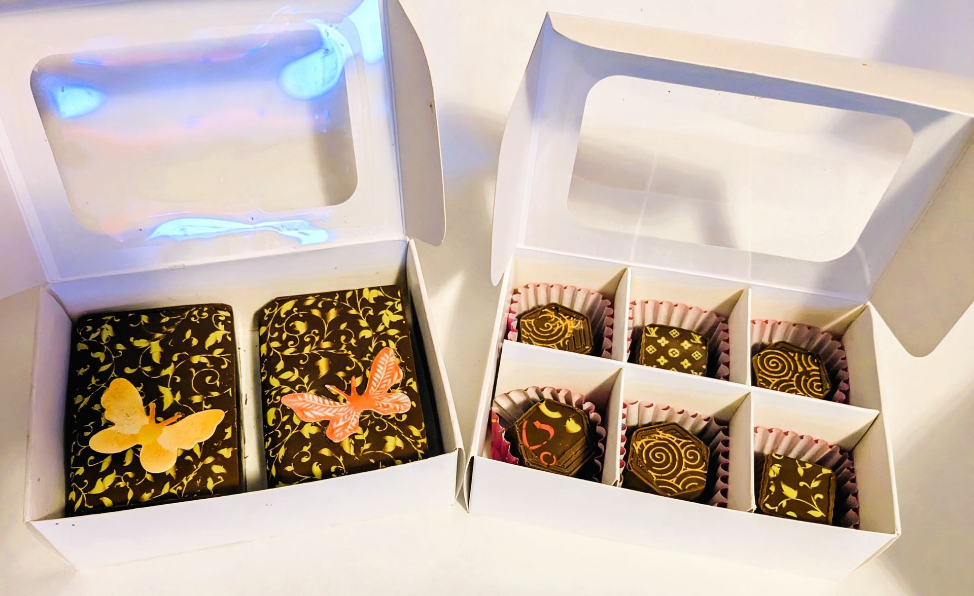 Two boxes of assorted chocolates with butterfly designs.