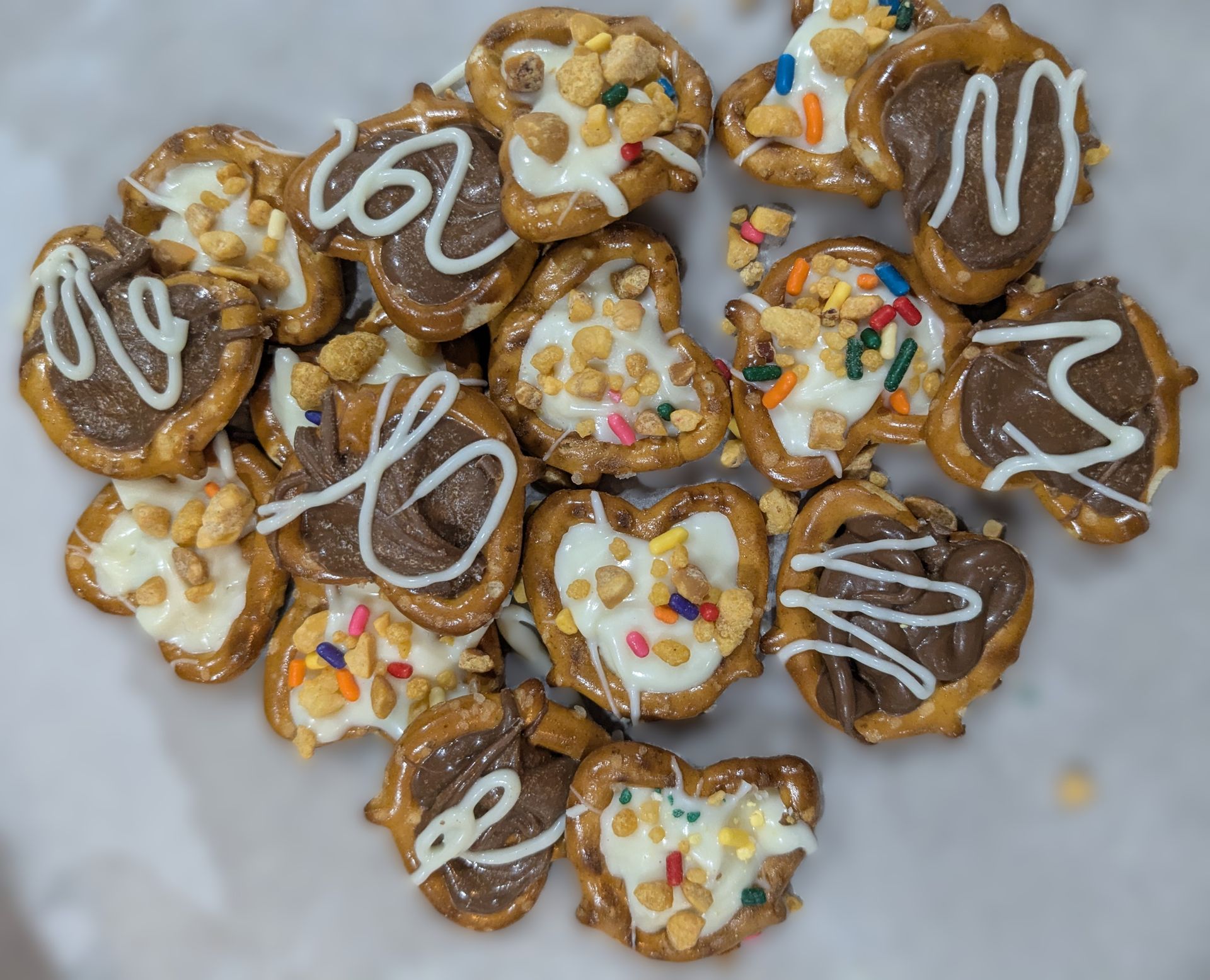 GamGams Pretzel treats: chocolate and white chocolate covered, with sprinkles and peanuts on parchment paper.