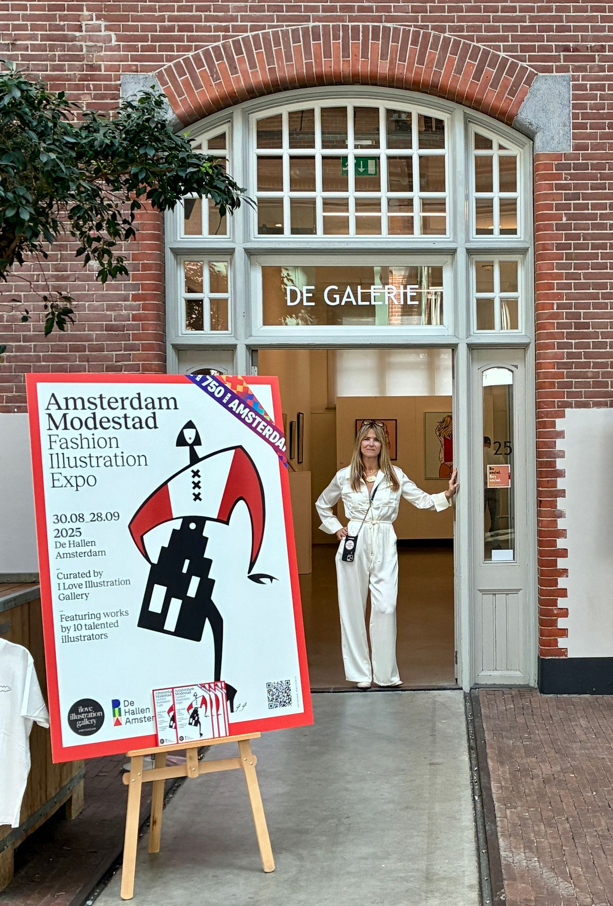 Woman in white jumpsuit stands in gallery doorway with 