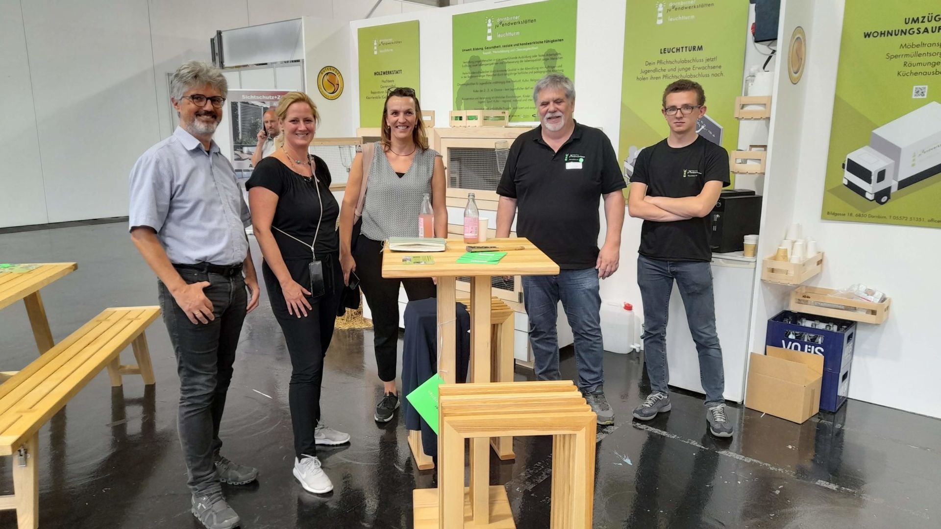 Eine Gruppe von Menschen steht in einem Raum um einen Tisch herum.