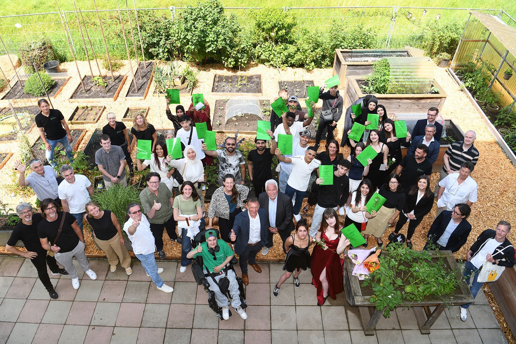 Eine große Gruppe von Menschen posiert für ein Foto und hält dabei grüne Papiere in den Händen.