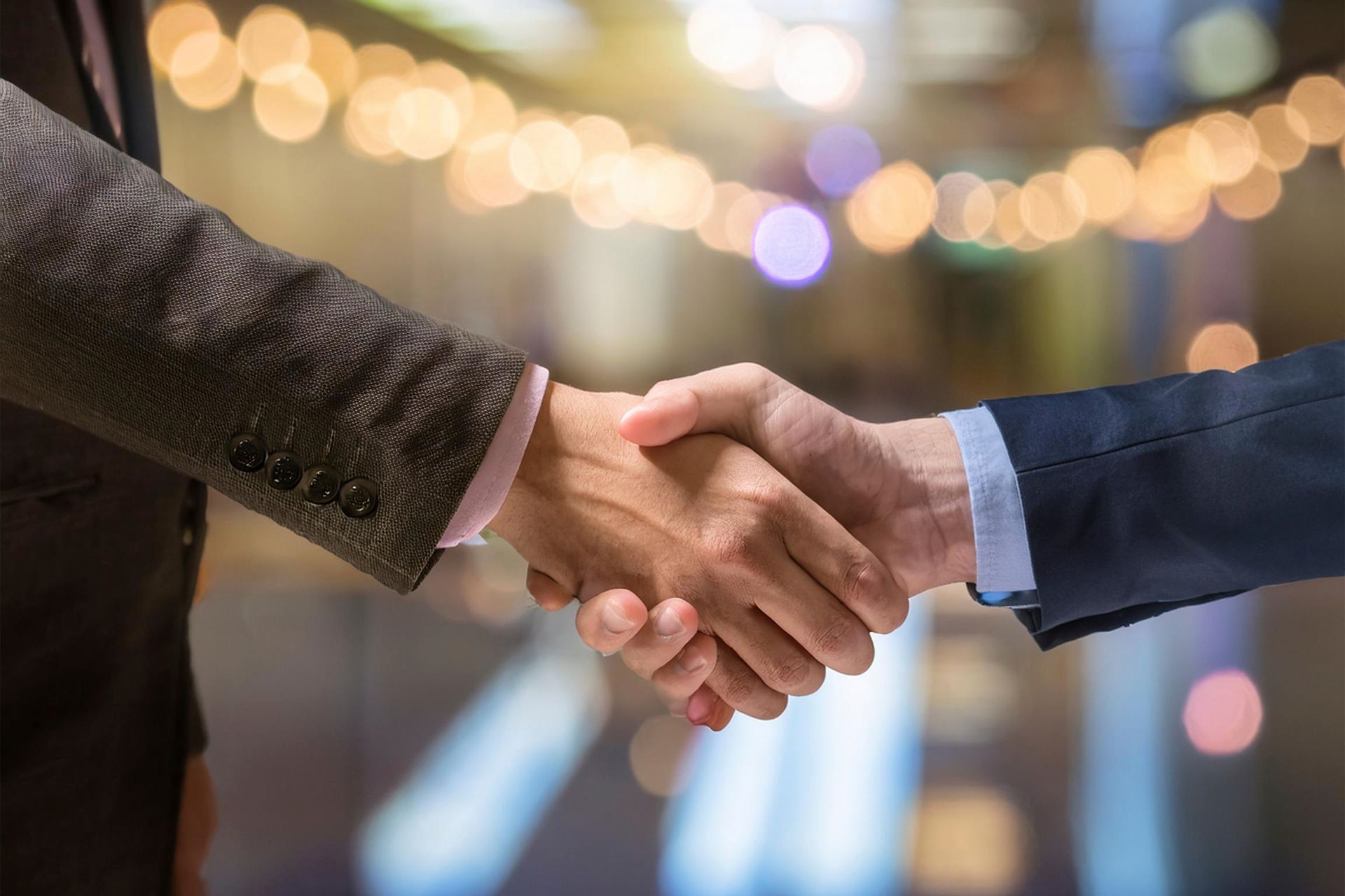 Zwei Geschäftsmänner schütteln sich vor einem unscharfen Hintergrund die Hände.