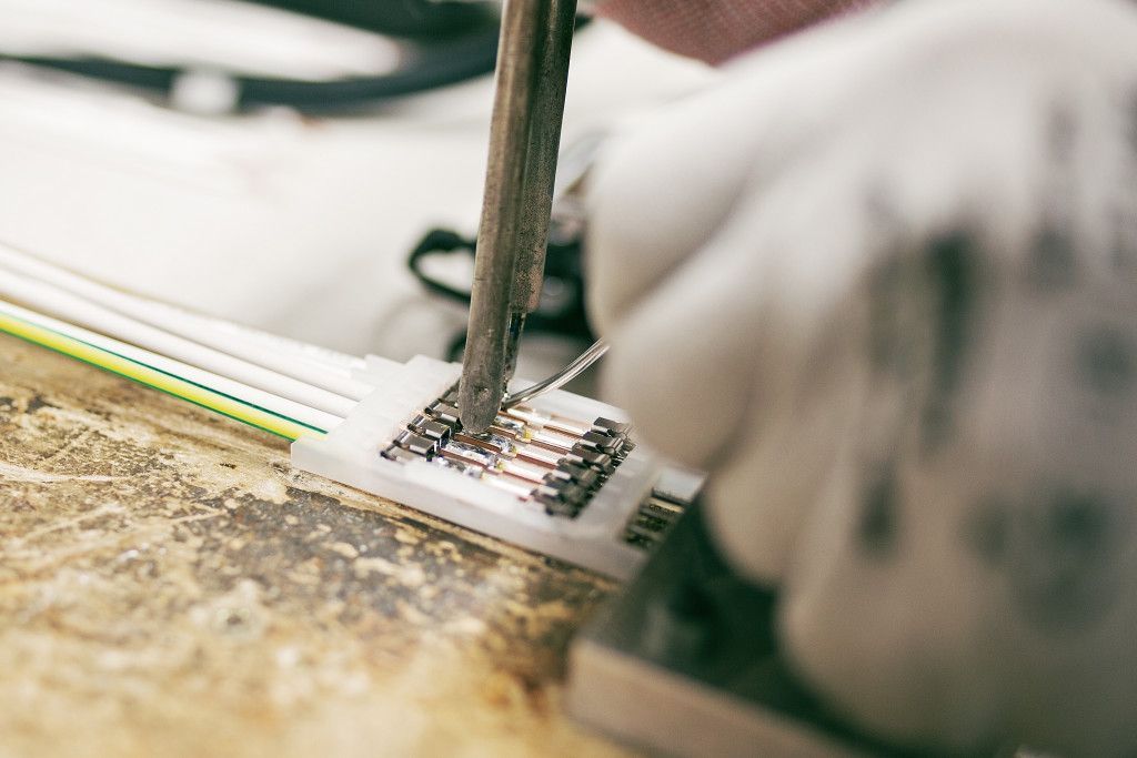 Eine Person lötet ein elektronisches Gerät mit einem Lötkolben.