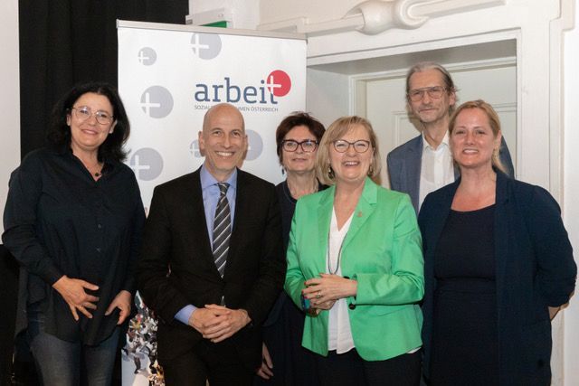 Eine Gruppe von Menschen steht vor einem Schild mit der Aufschrift „Arbeit“