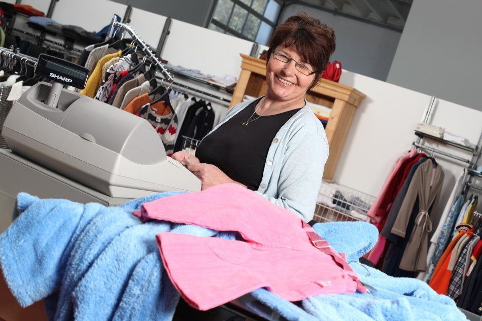 Eine Frau sitzt vor einer Kasse in einem Bekleidungsgeschäft