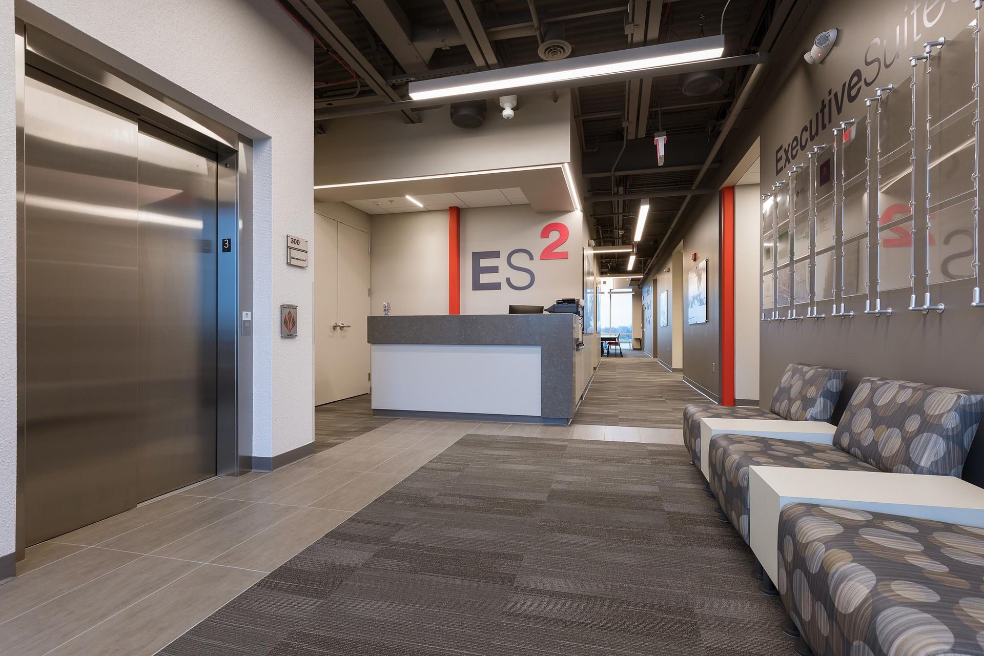 A lobby with a couch and a elevator and a sign that says es2
