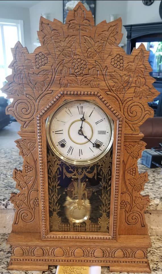 A wooden clock is sitting on a counter in a living room.
