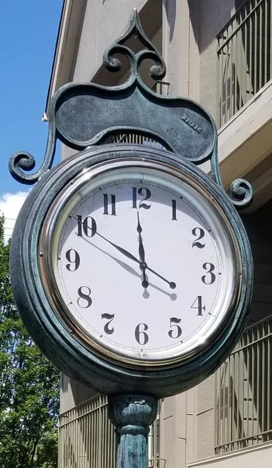A clock on a pole outside of a building shows the time as 5:00