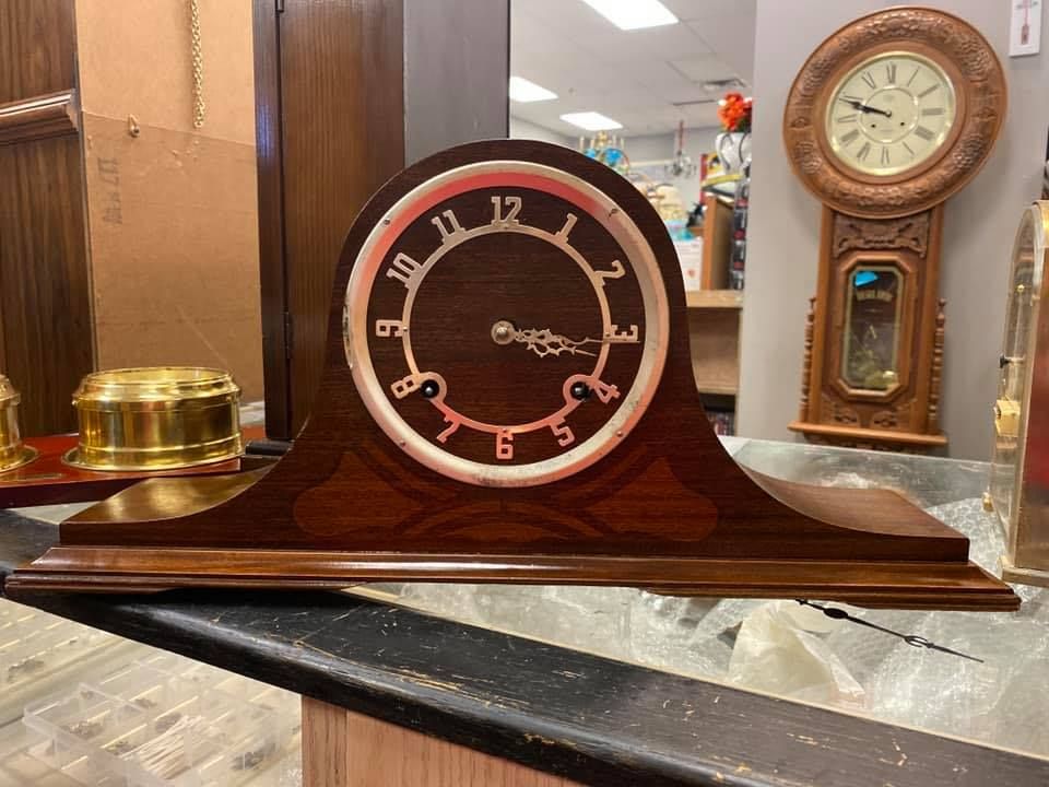 A wooden clock is sitting on a counter in a store.