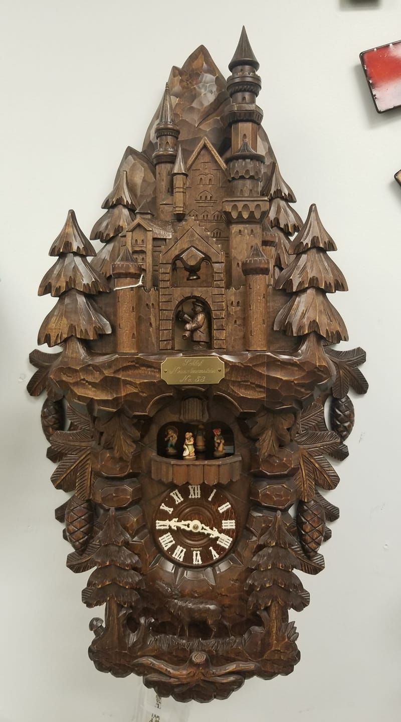 A wooden cuckoo clock with a castle and trees on it