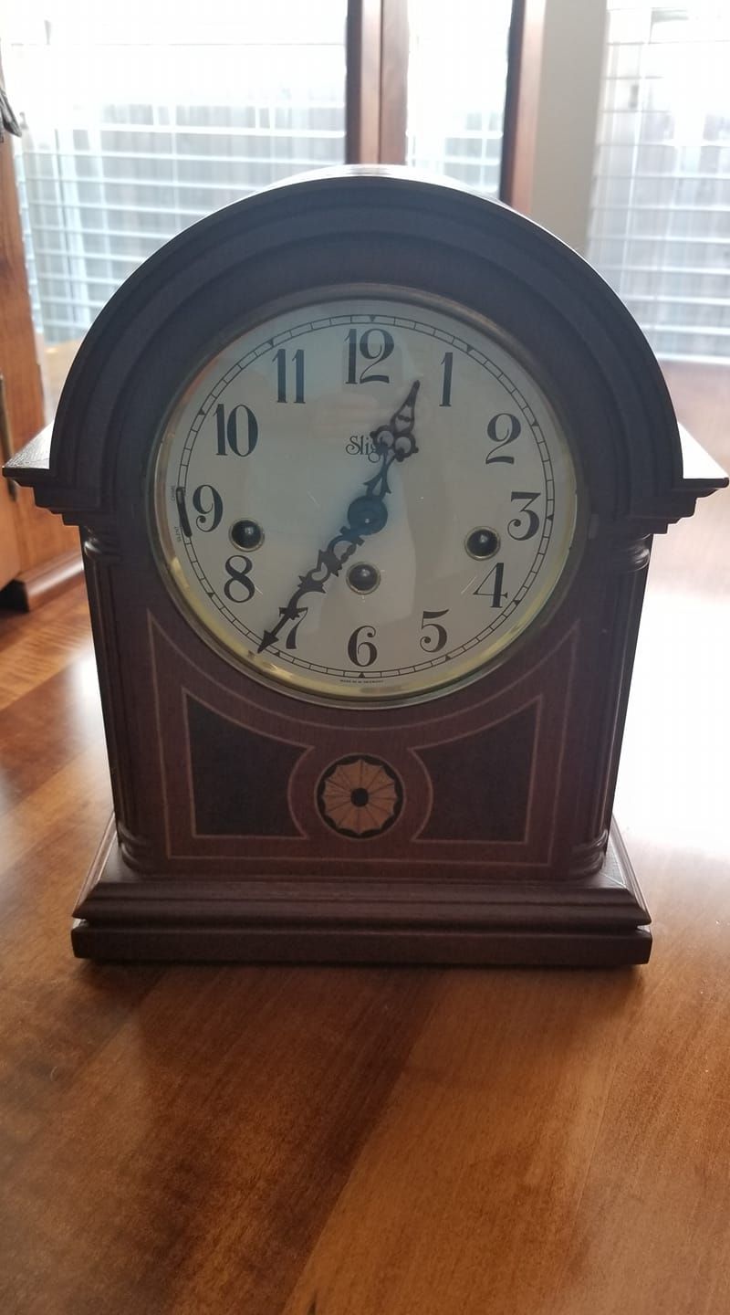 A wooden clock is sitting on a wooden table.