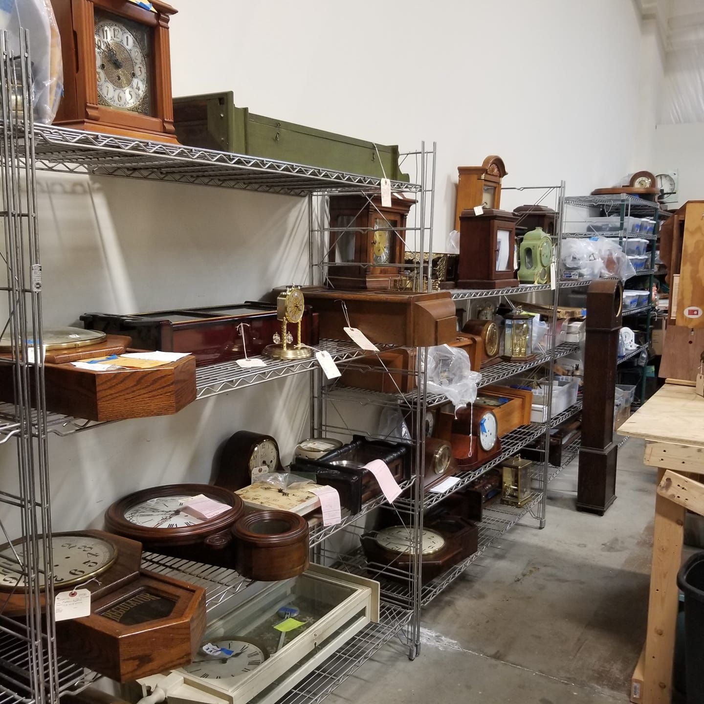 A bunch of clocks are on shelves in a room