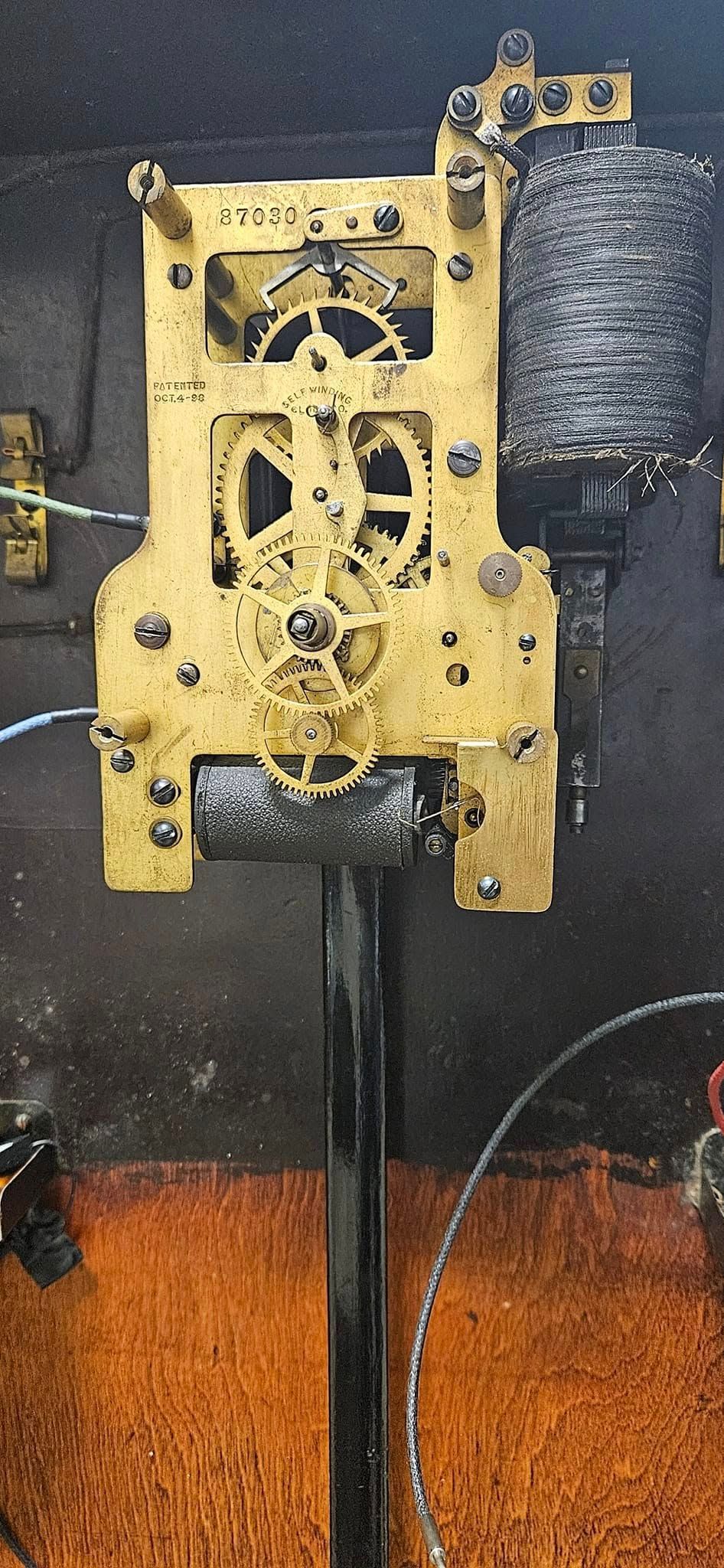 A close up of a clock mechanism on a pole.