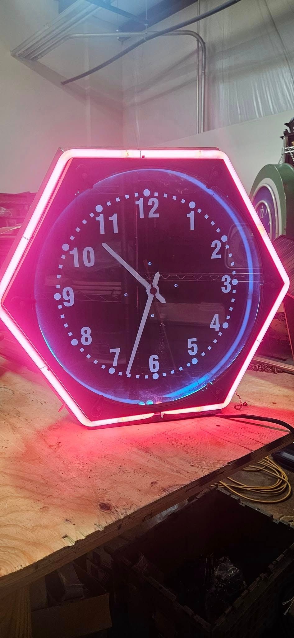 A neon clock is sitting on top of a wooden table.