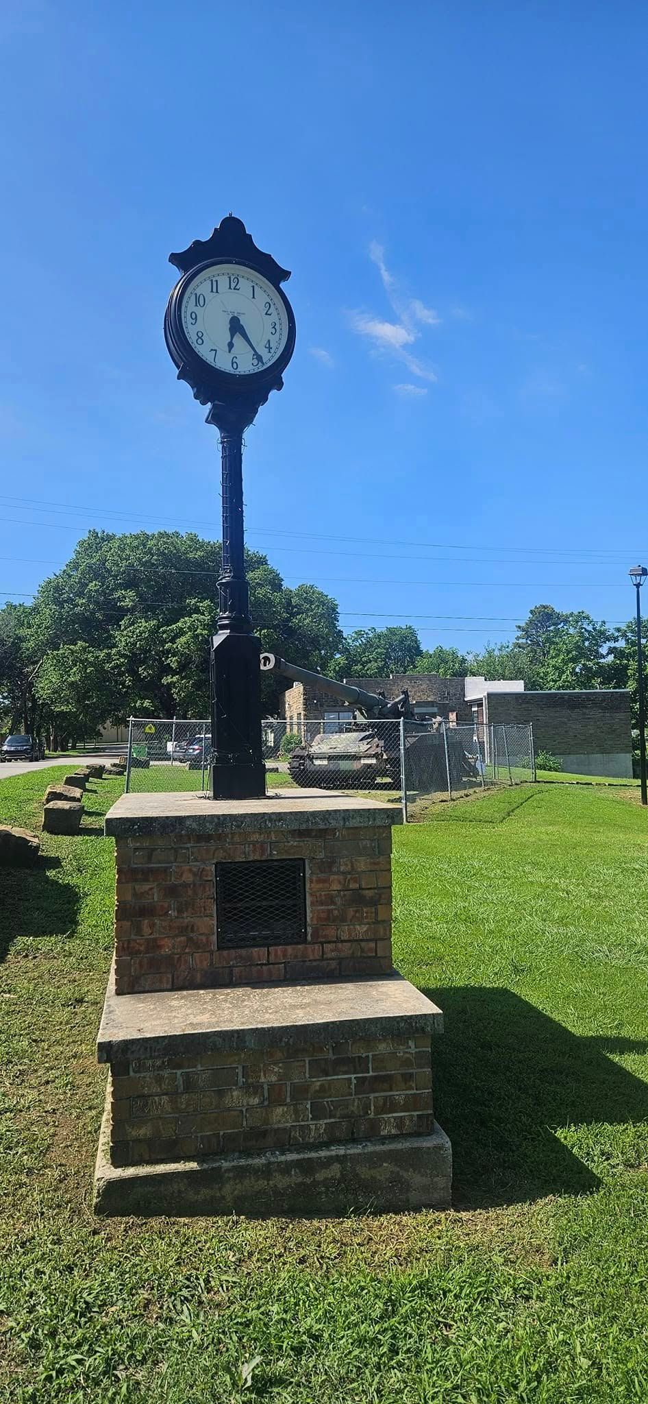 A large clock is sitting in the middle of a grassy field.