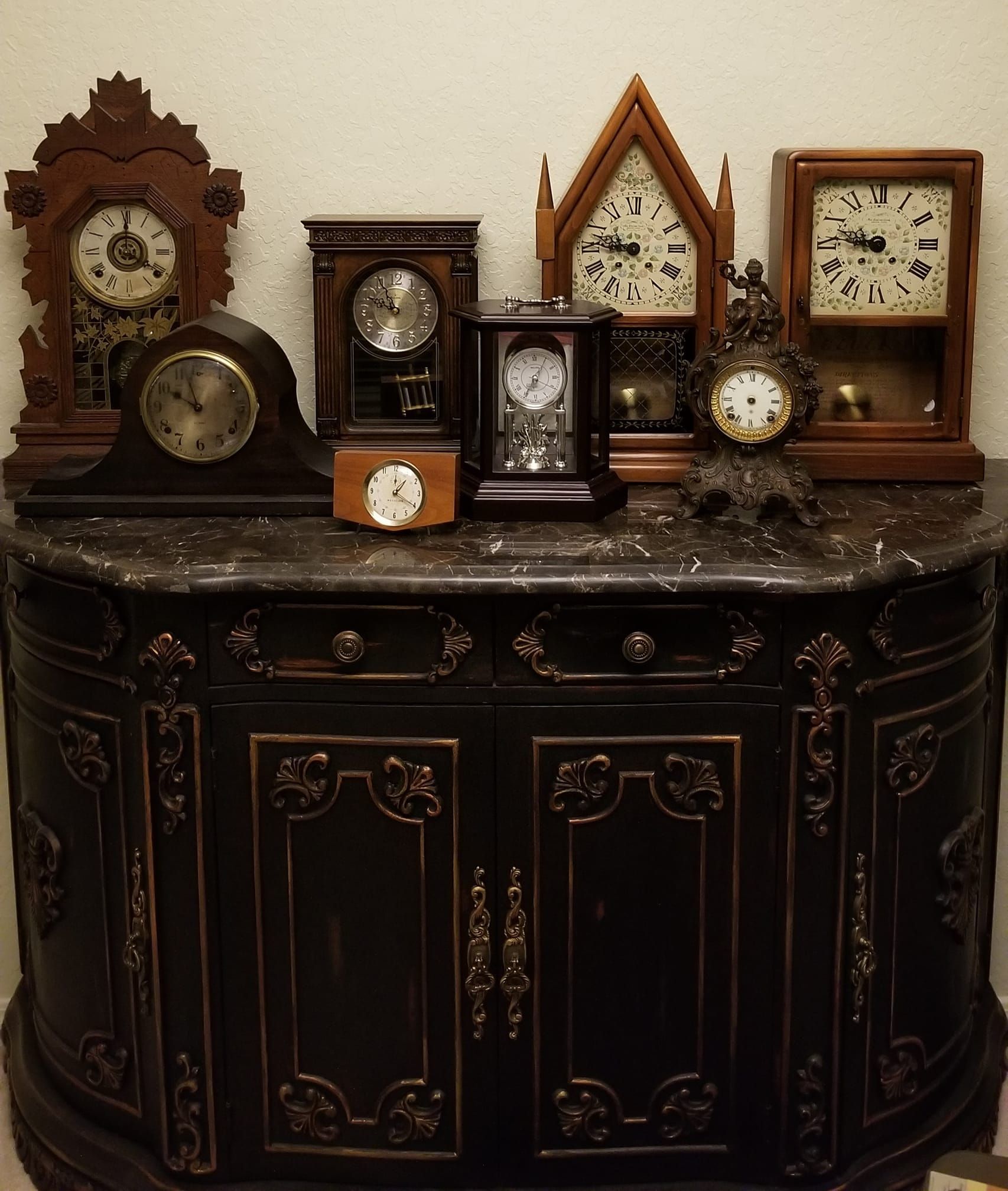 A collection of clocks on a dresser including one that says 10:08