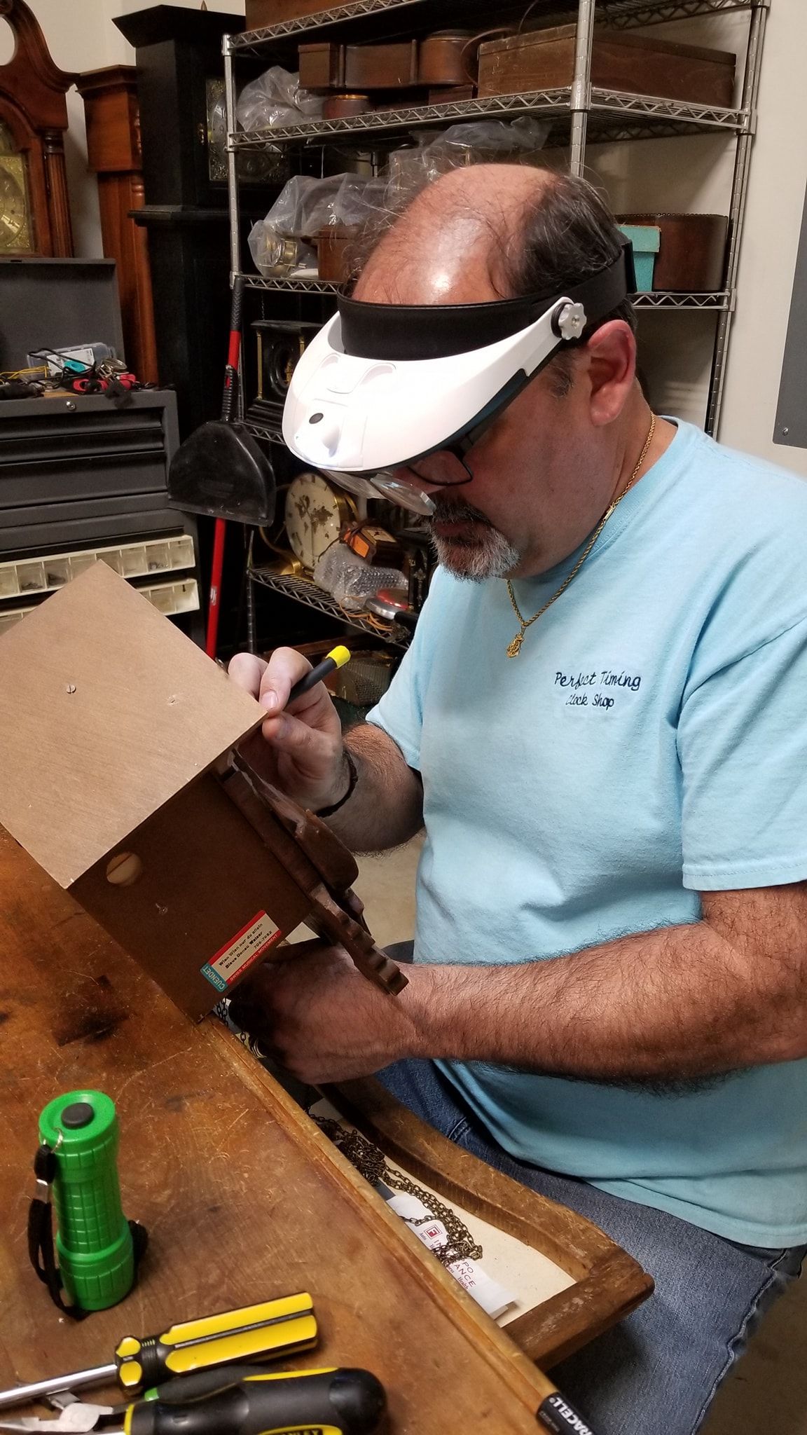 A man wearing a magnifying glass is working on a cuckoo clock.
