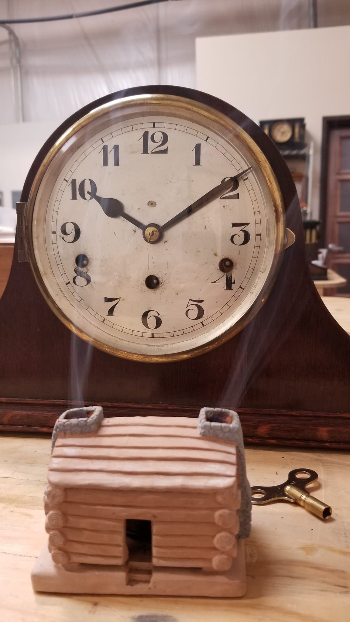 A clock with a wooden house on top of it