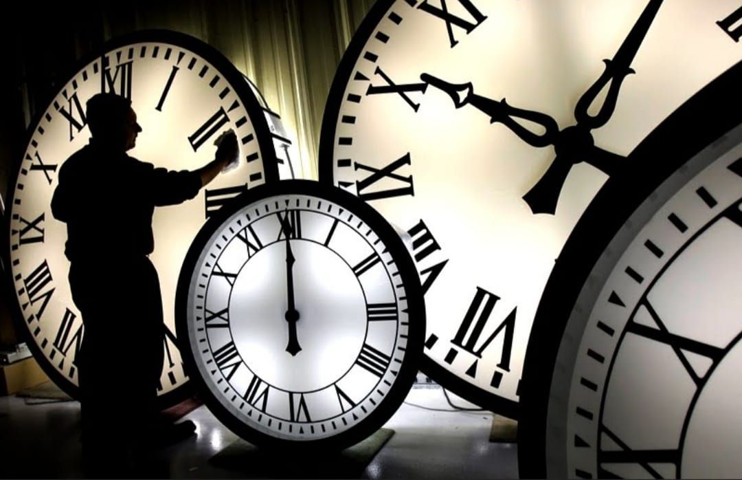 A man adjusts a clock with roman numerals on it