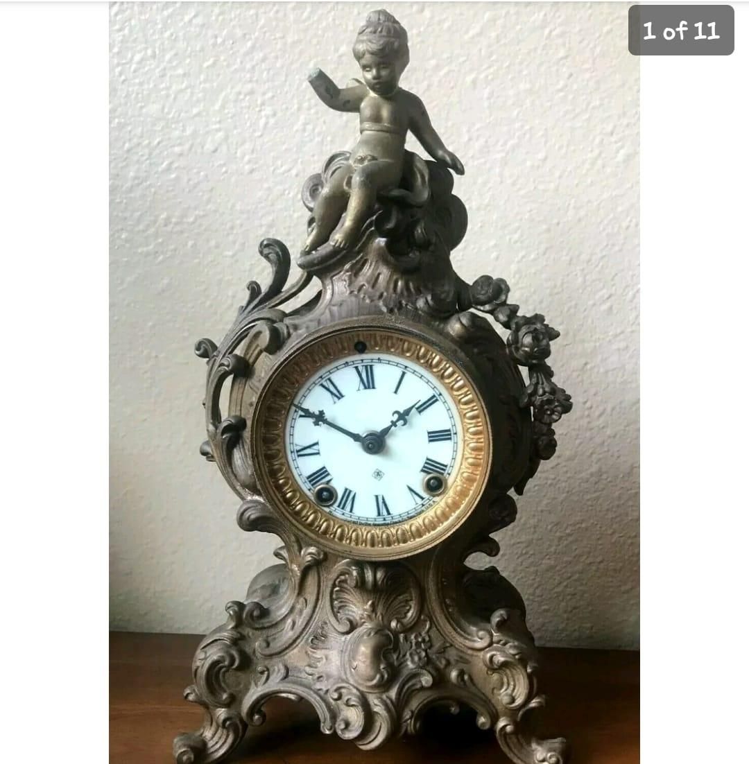 An antique clock with a cherub on top of it