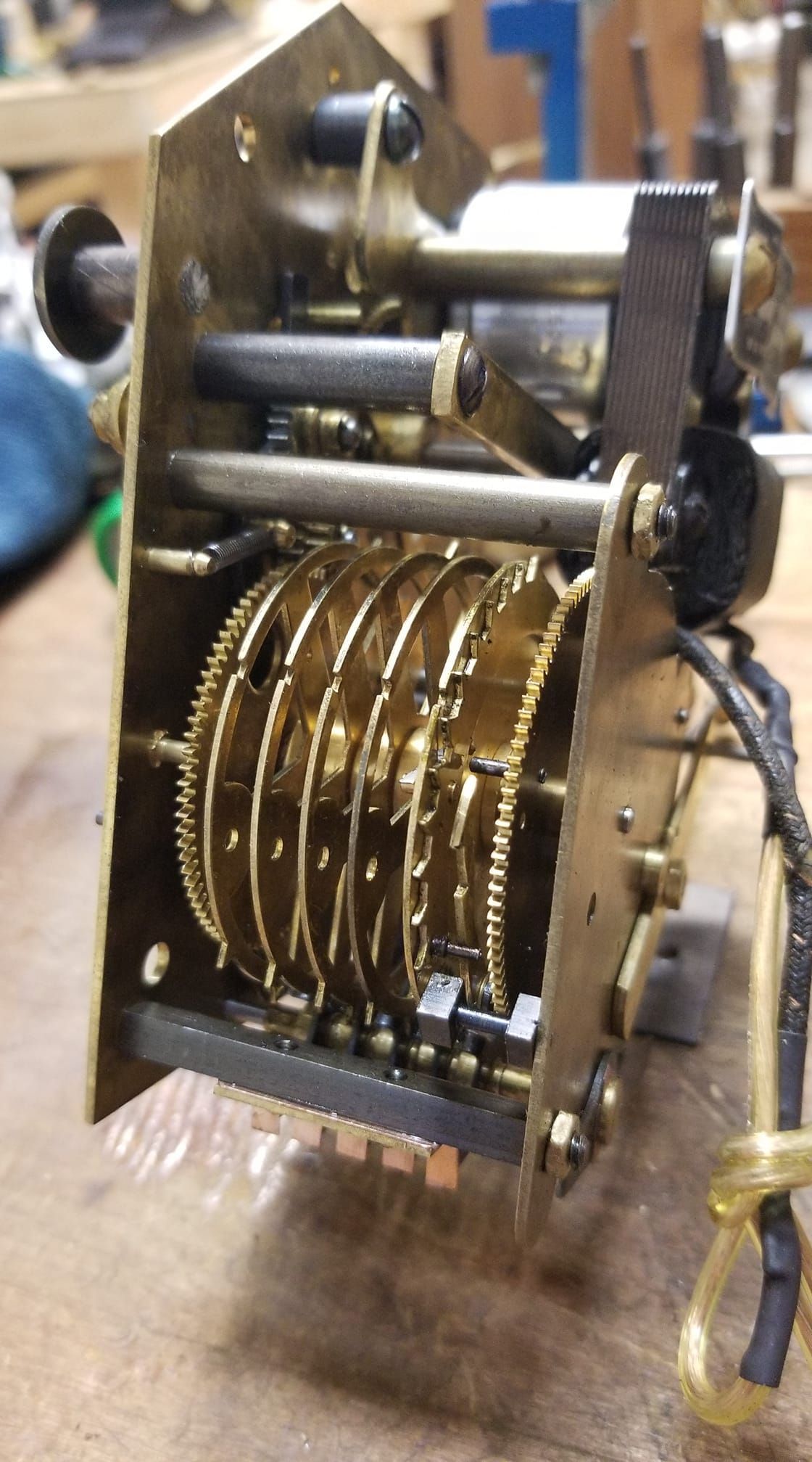 A close up of a clock mechanism on a wooden table.