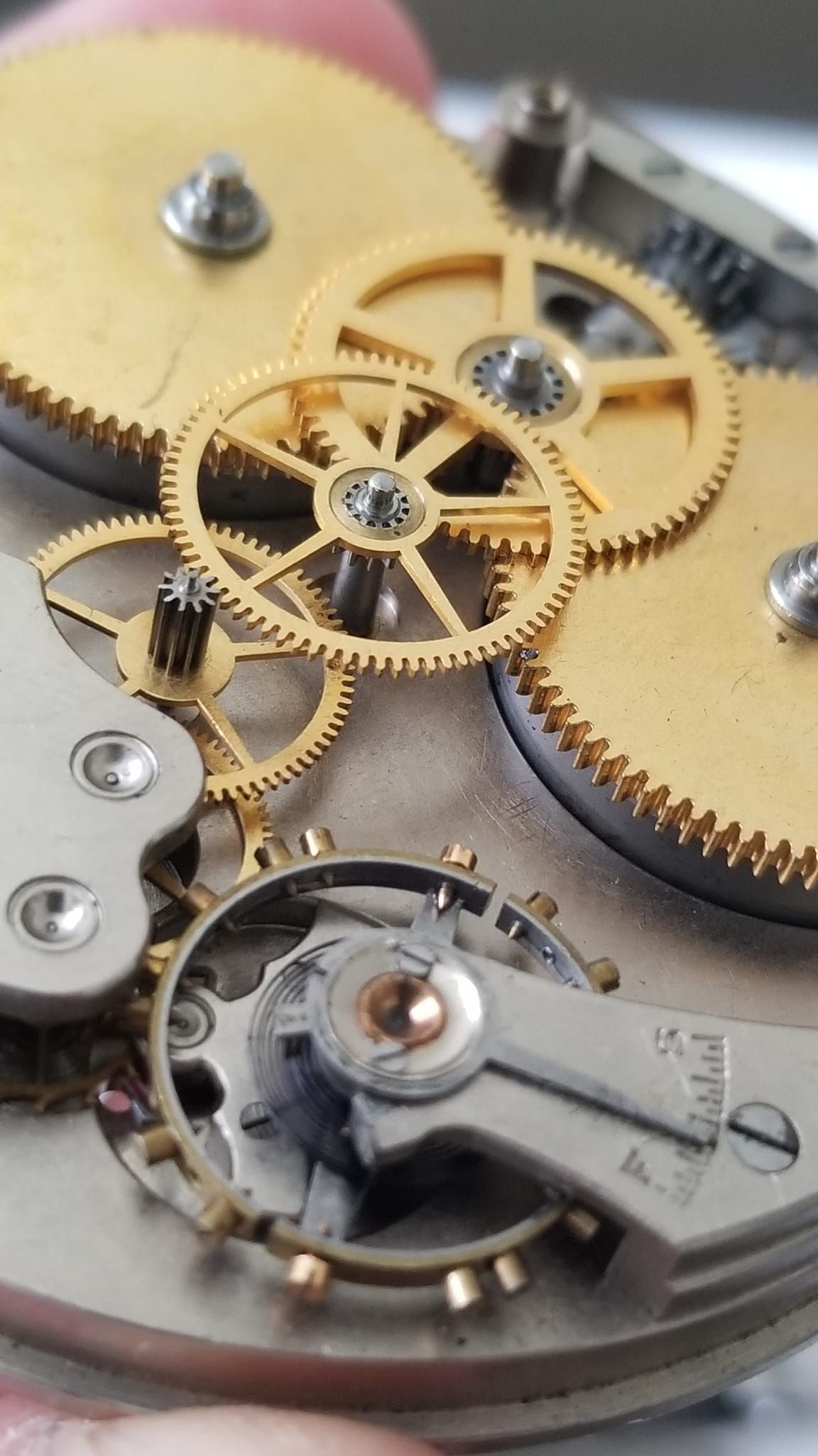 A person is holding a watch with a lot of gears on it.